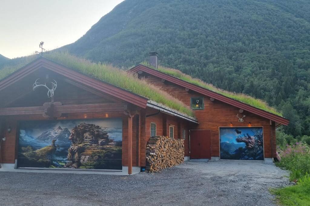 un edificio con techo de césped con montañas al fondo en Garasjeleilighet med kort vei til flott natur, Måndalen, Rauma, en Sæbø