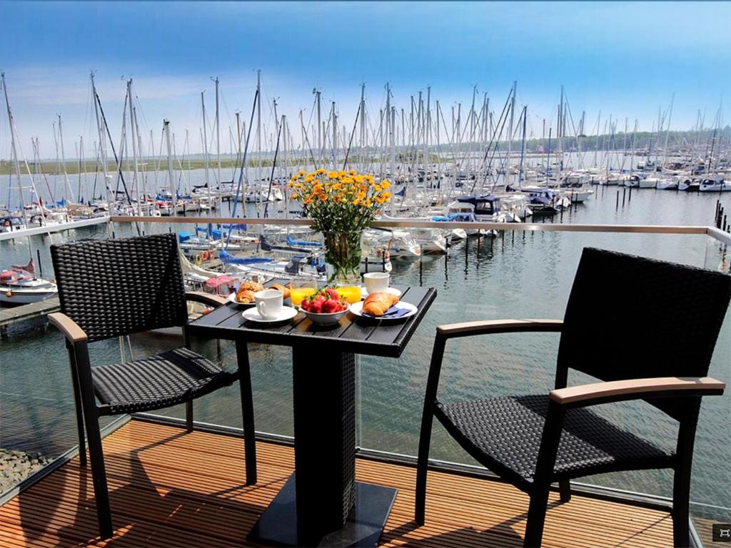 ハイリゲンハーフェンにあるOstsee - Appartement Nr 50 "Meerblick" am Yachthafen im Strand Resortのマリーナ付きのデッキ(テーブル、椅子付)