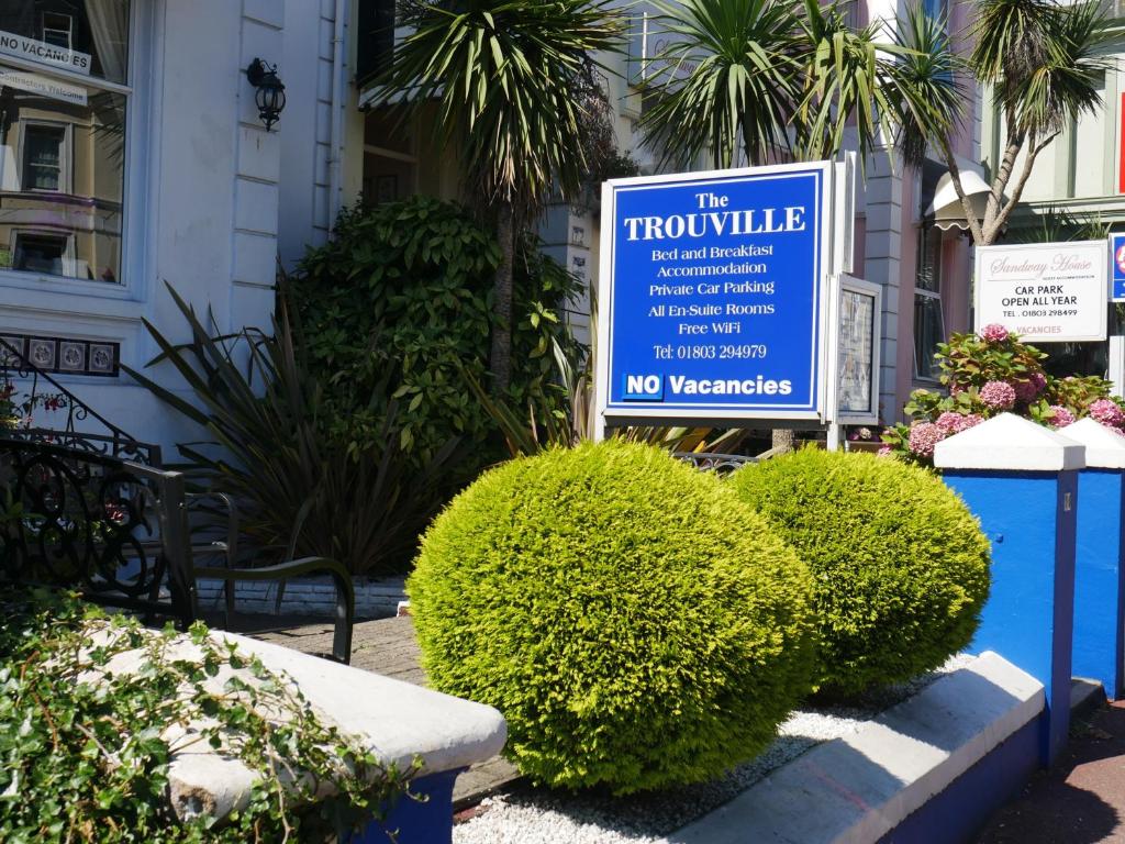 una señal frente a un edificio con arbustos en The Trouville, en Torquay