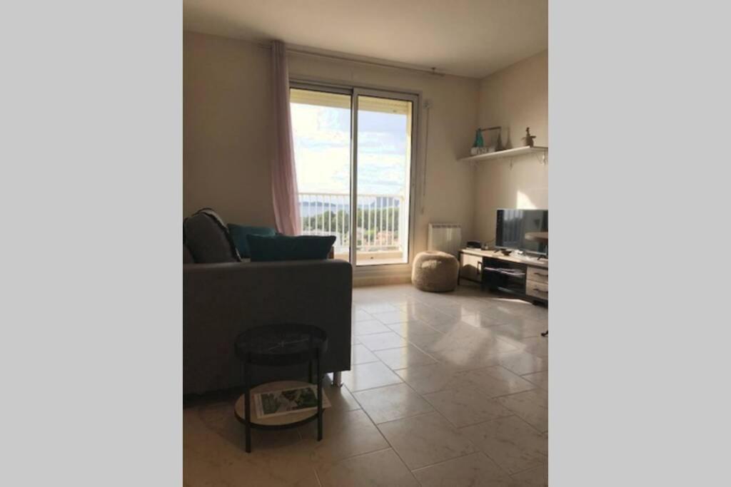 een woonkamer met een bank en een groot raam bij Appartement T1 Balcon vue mer in La Ciotat