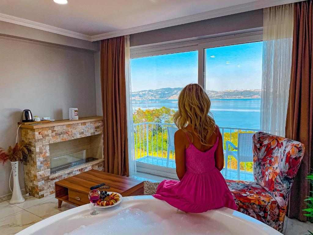 a woman sitting in a chair looking out a window at Sapanca View Hotel in Sapanca