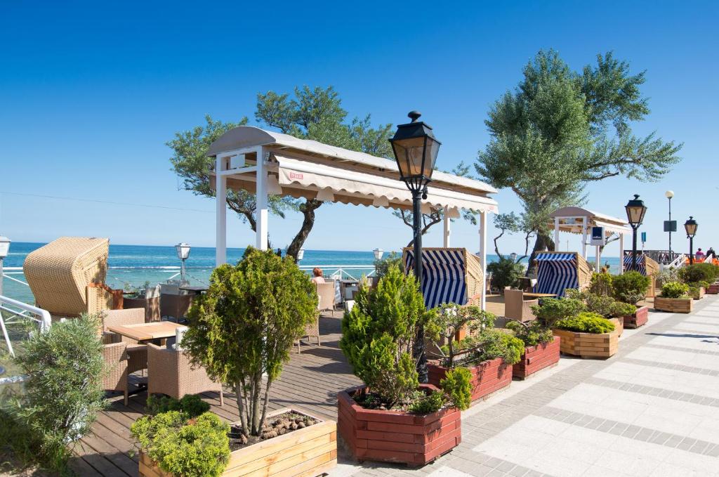 patio z krzesłami i drzewami oraz oceanem w obiekcie Meduza Hotel & Spa w mieście Mielno