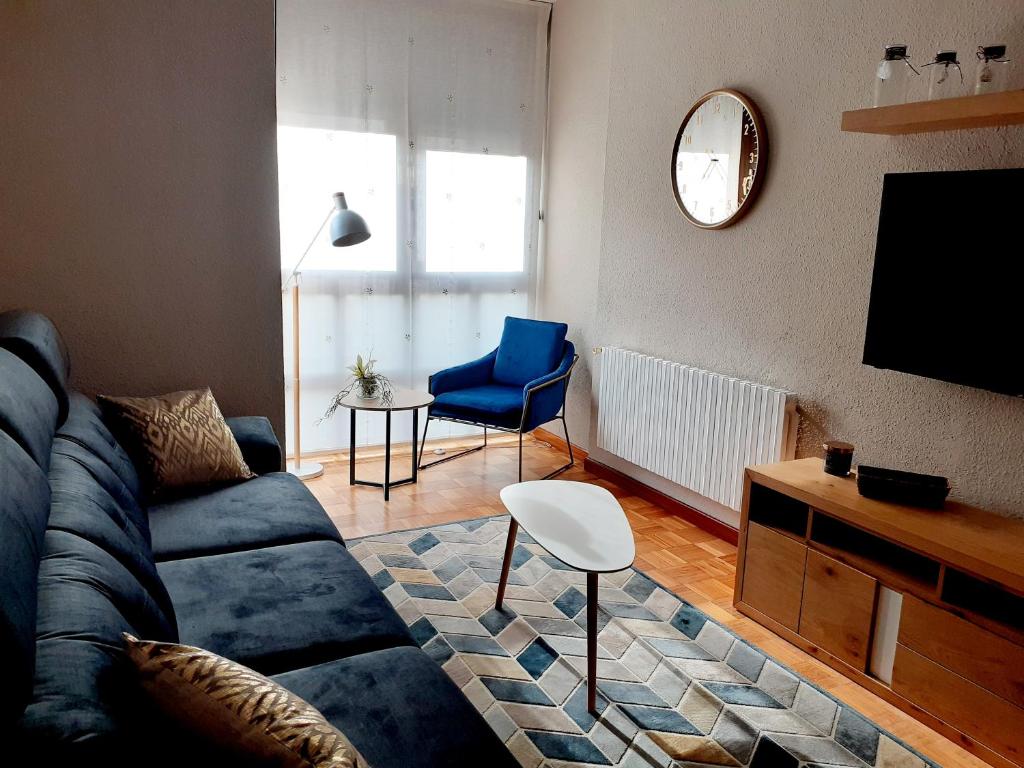 een woonkamer met een blauwe bank en een tv bij Adosado Marblés con Txoko y Wifi in Ezcaray