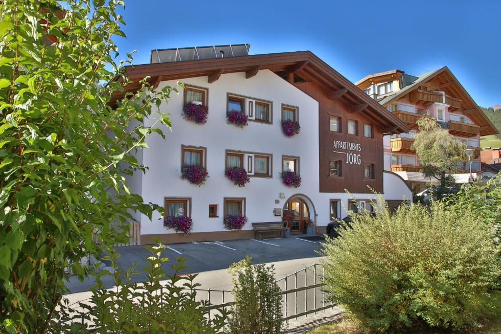 un edificio blanco con flores en las ventanas en Apartmenthaus Jörg, en Serfaus