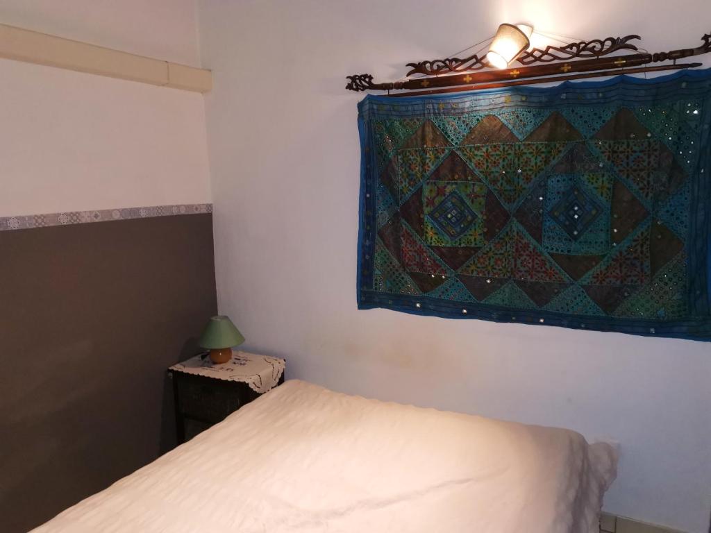 1 Schlafzimmer mit einem Bett und einem Fenster mit einer Decke in der Unterkunft Appartement d'une chambre avec vue sur la mer jardin clos et wifi a Saint Leu a 5 km de la plage in Saint-Leu