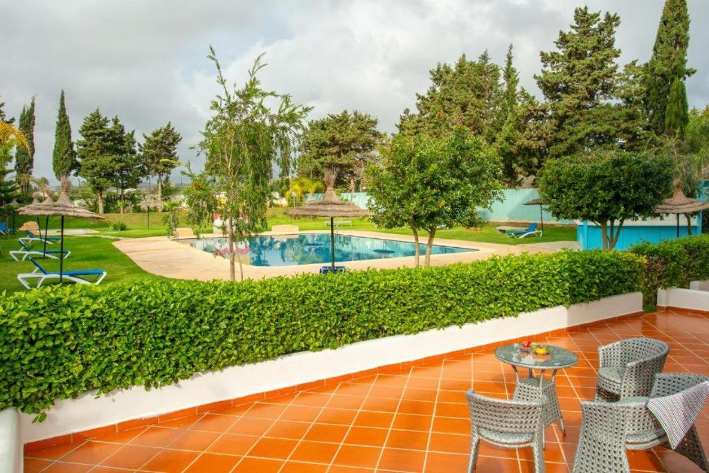 een patio met een tafel en stoelen en een zwembad bij Résidence Hôtelière Riviera Beach in Cabo Negro