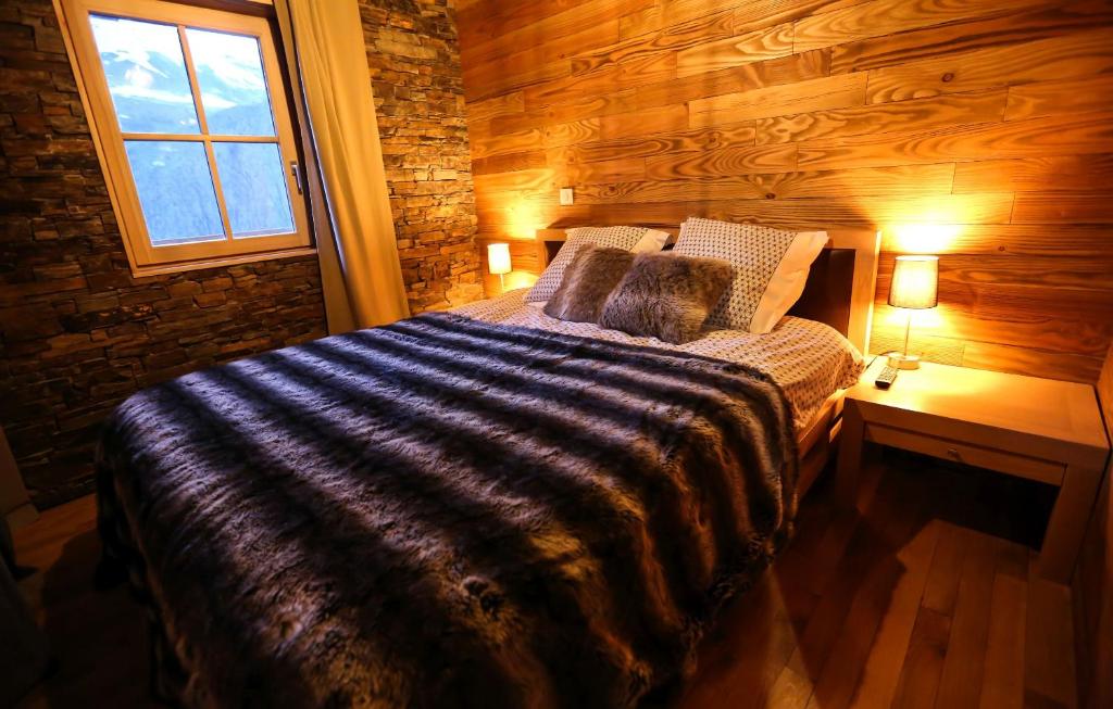 a bedroom with a bed with a wooden wall at Odalys Chalet Les Lions Blancs in Valloire