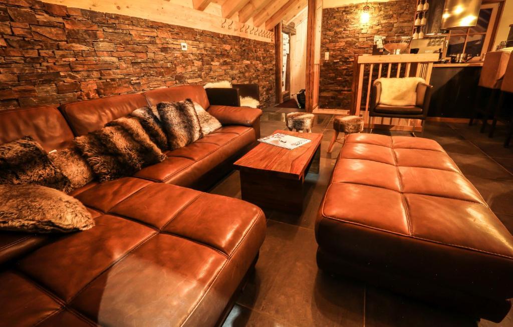 a living room with a leather couch and a table at Odalys Chalet Les Lions Blancs in Valloire