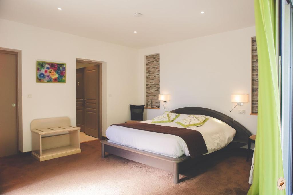 ein Schlafzimmer mit einem Bett und einem Stuhl darin in der Unterkunft Domaine de l'Echassier, The Originals Relais in Châteaubernard