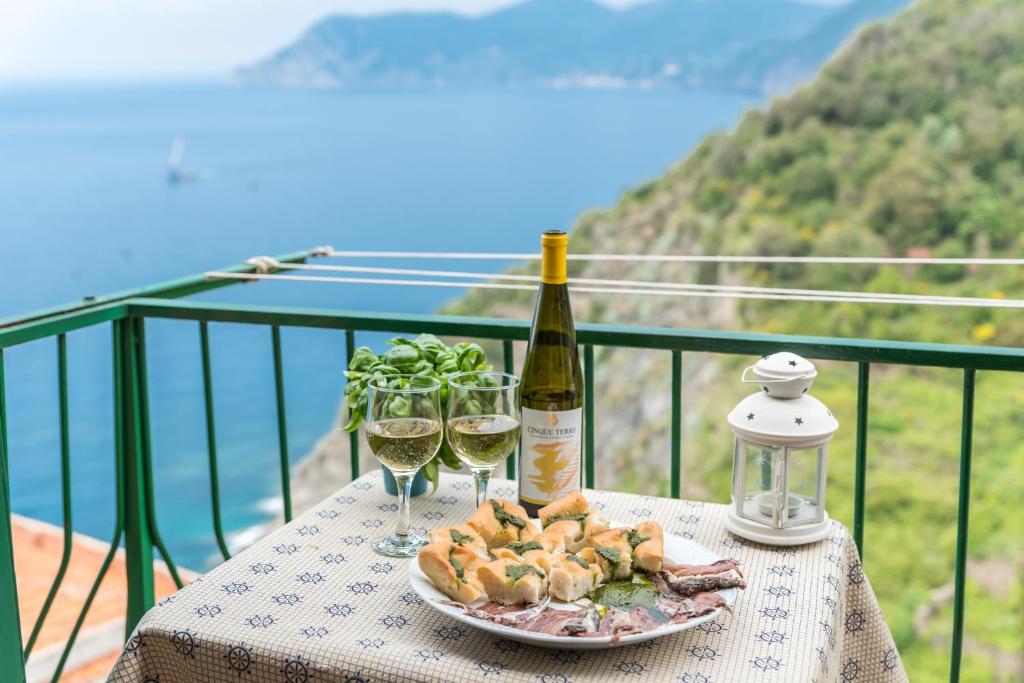 un tavolo con un piatto di cibo e due bicchieri di vino di Affittacamere Arbasia De Ma, Terre Marine a Corniglia