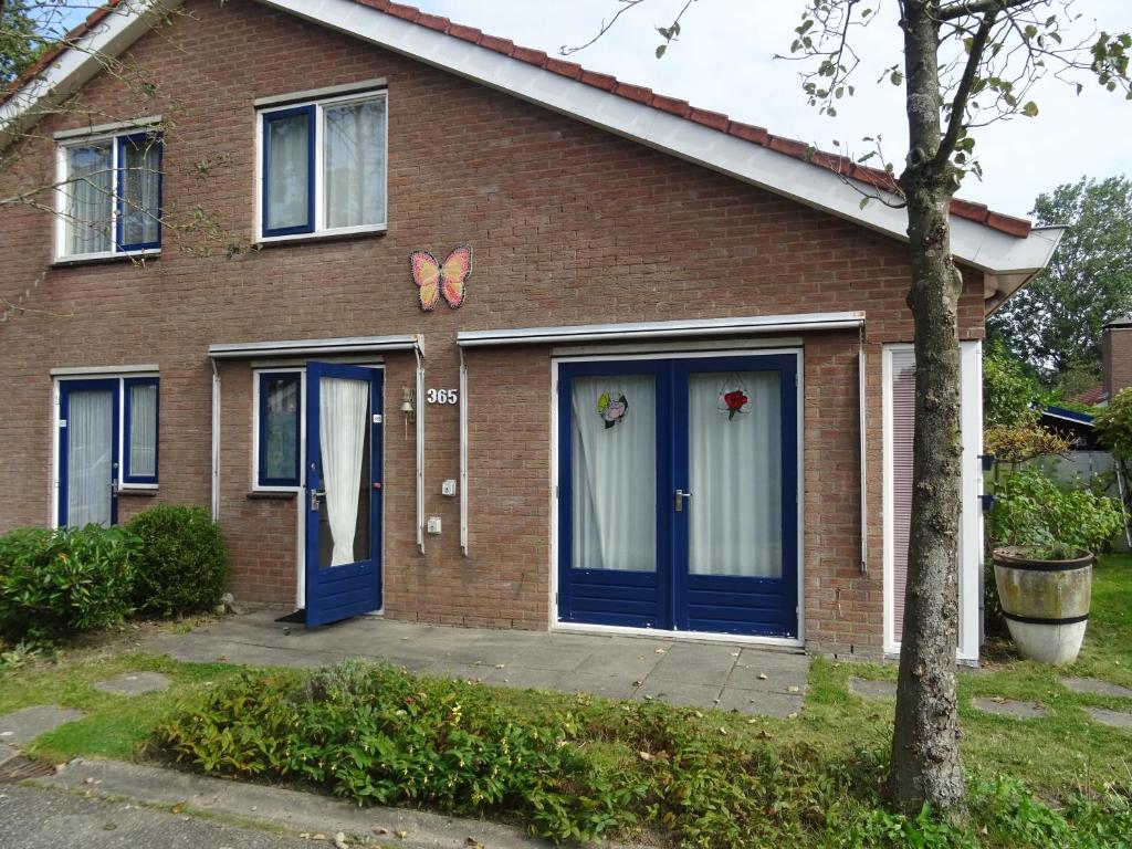 una casa con porte blu e farfalle sopra di Kustverhuur, Park Schoneveld, Strandparel 365 a Breskens