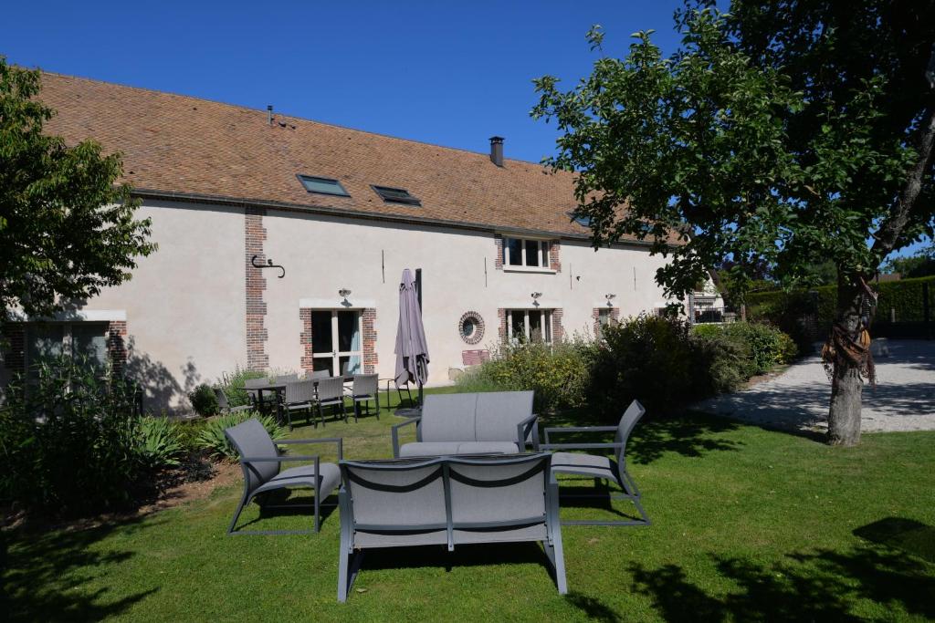 una mesa y sillas frente a un edificio en Gîte LA MELINOTHE - 12 personnes - Grand gîte de charme indépendant 5 étoiles, en Paisy-Cosdon