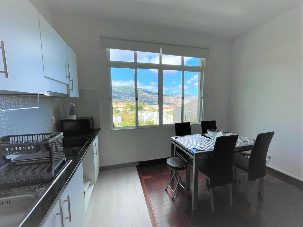 a kitchen with a table with chairs and a window at Shining in Funchal