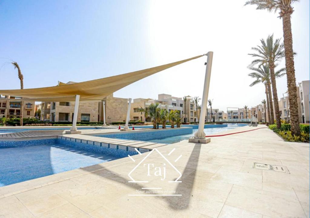 a swimming pool in a resort with palm trees at Taj Home, Mangroovy, pool view, free beach access with nanny's room in Hurghada