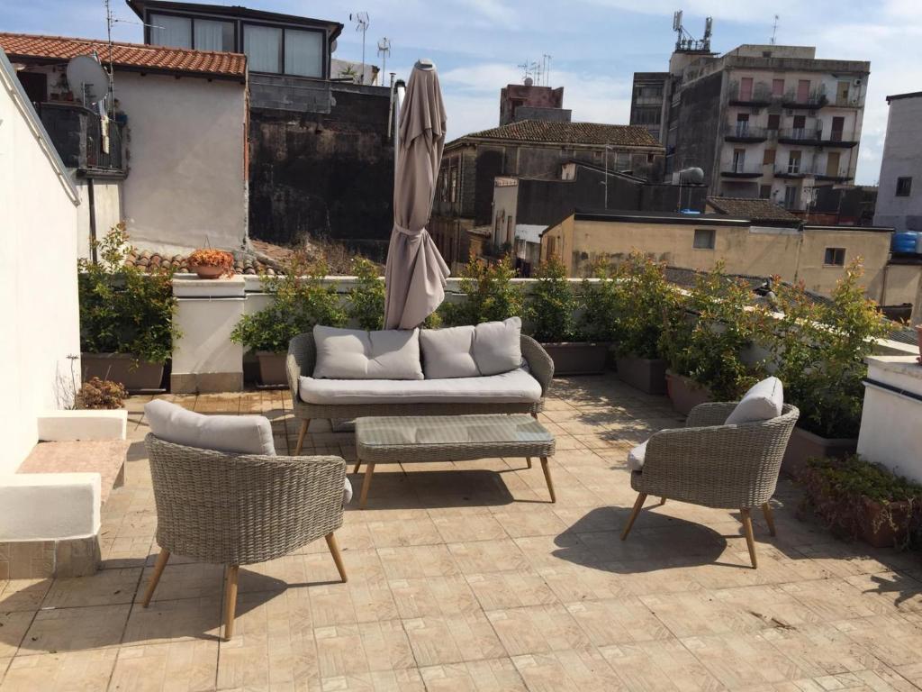 un patio con un divano, due sedie e un ombrellone di Old Catania Terrace a Catania