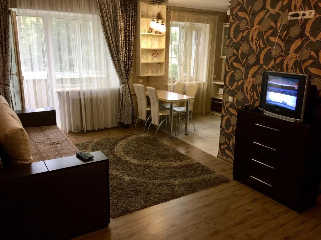 sala de estar con TV y mesa con sillas en Апартаменти en Chernihiv