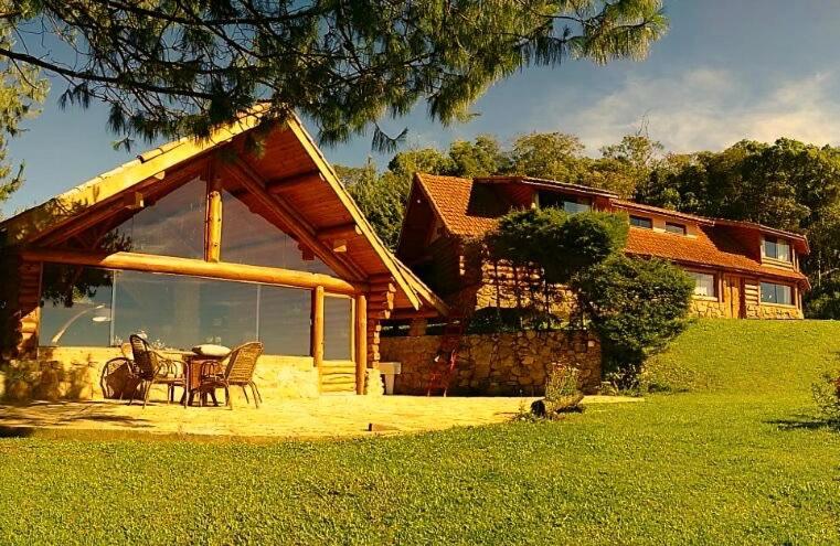 a house with a table and chairs in front of it at Log Cabin - Monte Verde in Camanducaia