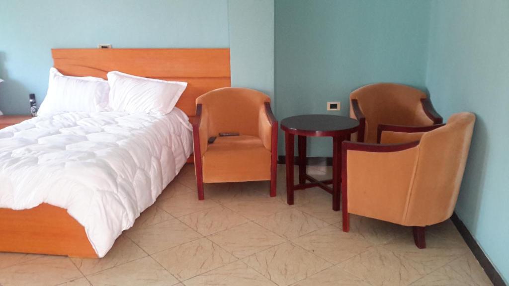 1 Schlafzimmer mit einem Bett, 2 Stühlen und einem Tisch in der Unterkunft Pure Pension in Addis Abeba