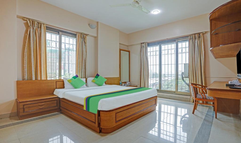 a bedroom with a bed and a desk and windows at Treebo Trend Welcome Apartments in Mumbai