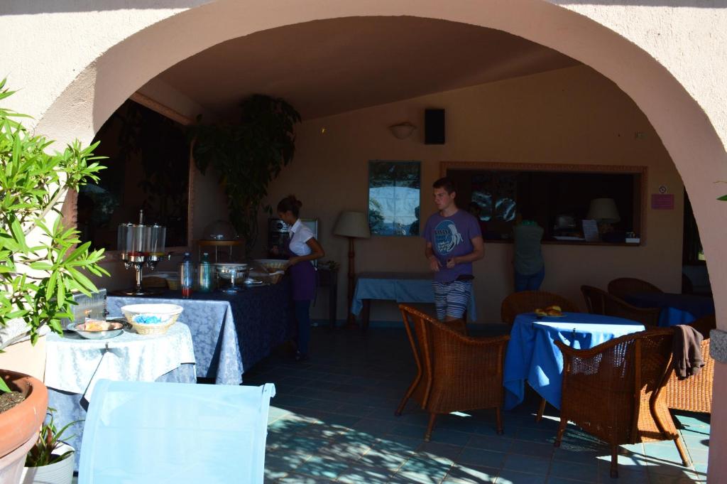 a couple of people standing in a restaurant with tables at Residence Fenicia in Villasimius