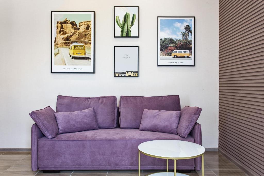 Havana ApartHotel في أوديسا: أريكة أرجوانية في غرفة مع صور على الحائط