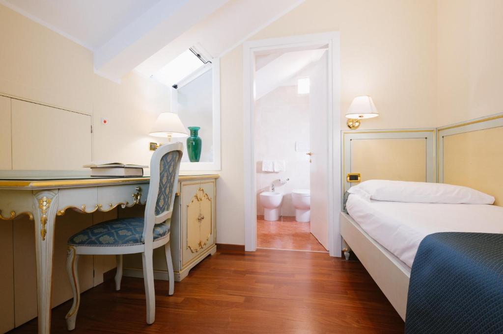 a bedroom with a bed and a desk with a chair at Hotel Do Pozzi in Venice