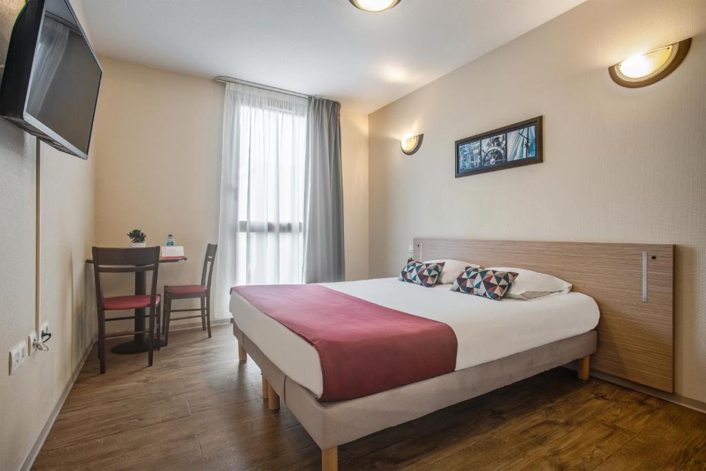 ニームにあるAppart'City Classic Nîmesのベッドとテーブルが備わるホテルルームです。