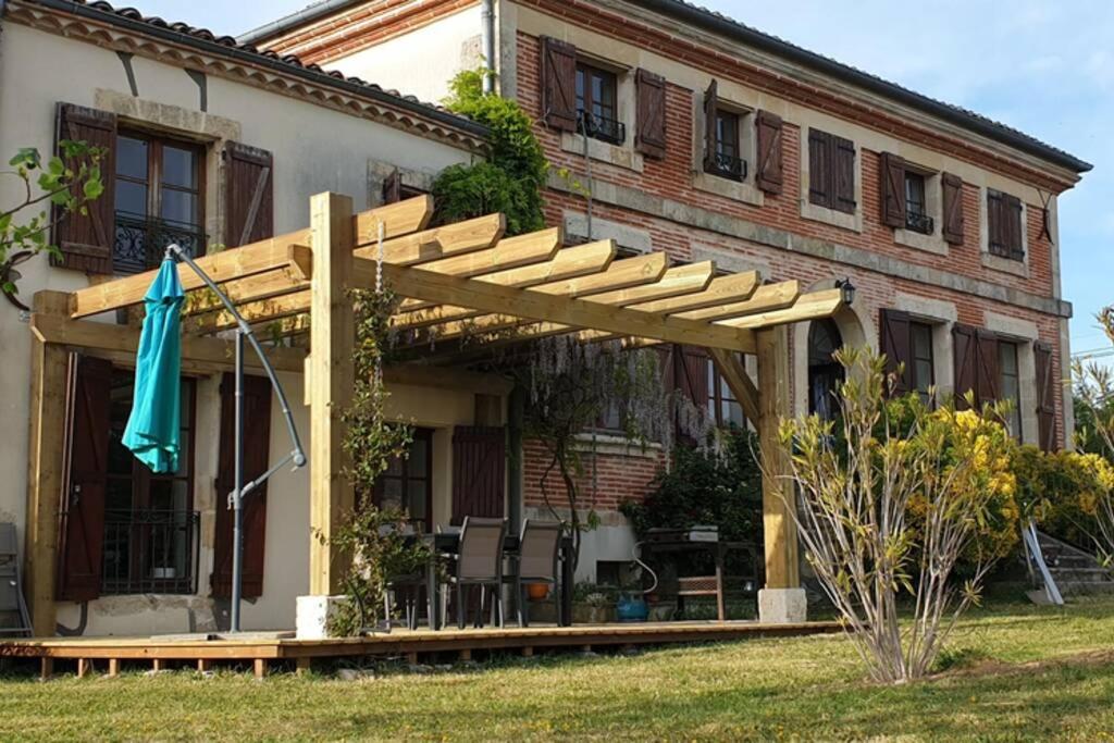 a wooden pergola on the side of a house at Maison de charme au coeur du Sud Ouest in Laplume