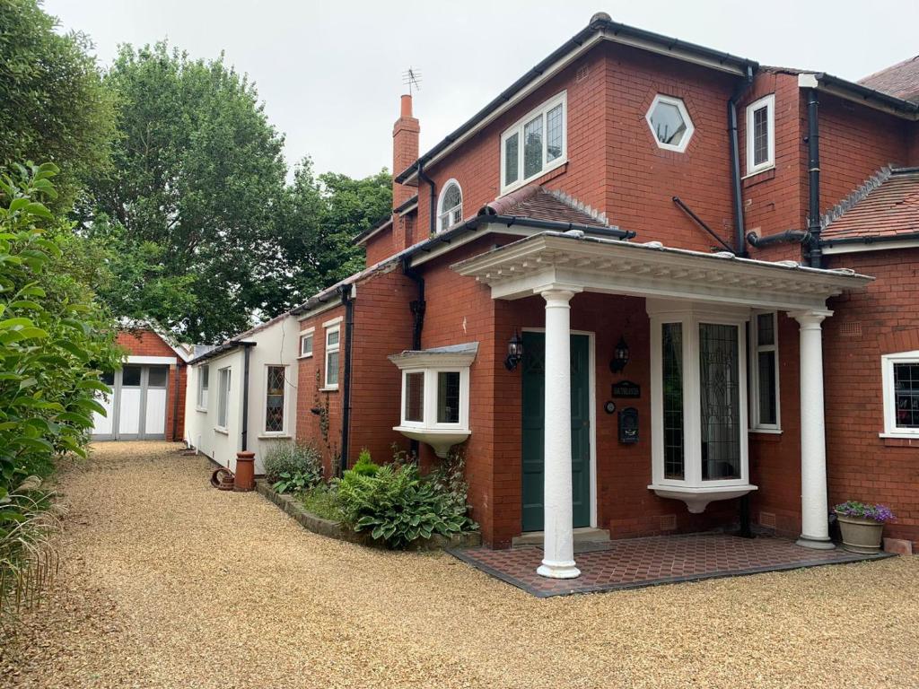 a red brick house with a white porch at Blackpool Abode - Southlands in Blackpool