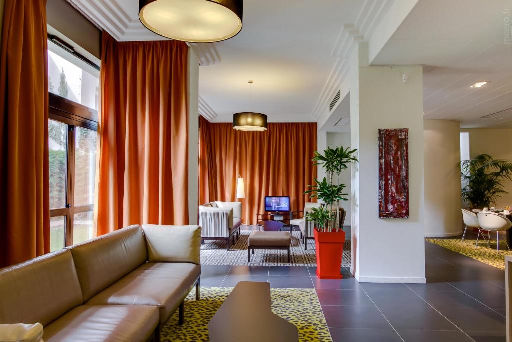 a living room with a couch and orange curtains at Privilège Appart Hôtel Saint Exupéry in Toulouse