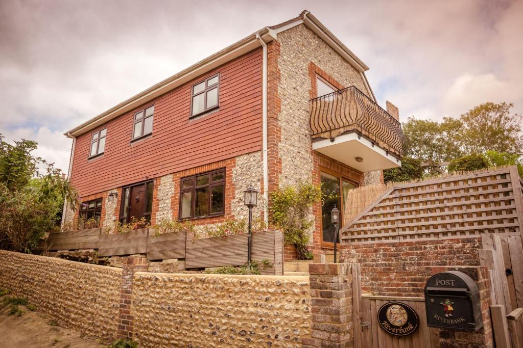 una casa de ladrillo con una valla delante de ella en Riverbank Cottage - idyllic riverside country cottage on South Downs en Alfriston