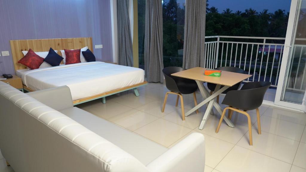 The White Orchid Luxury Service Apartments في إرناكولام: غرفة نوم بسرير وطاولة واريكة