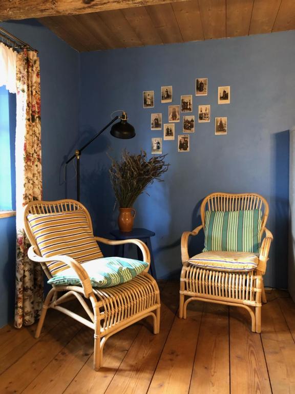 dwa wiklinowe krzesła w pokoju z niebieskimi ścianami w obiekcie Chałupa łowicka z XIX wieku w mieście Zduny