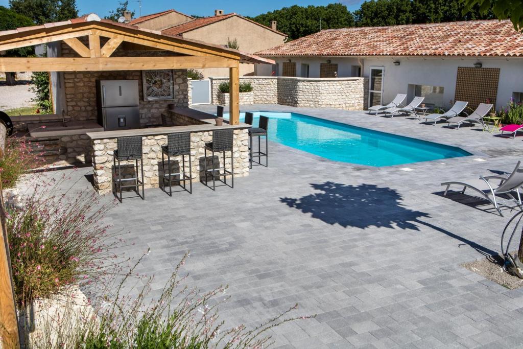 une terrasse avec une piscine et des chaises ainsi qu'une maison dans l'établissement Les Prairies de l'Encrême, à Céreste