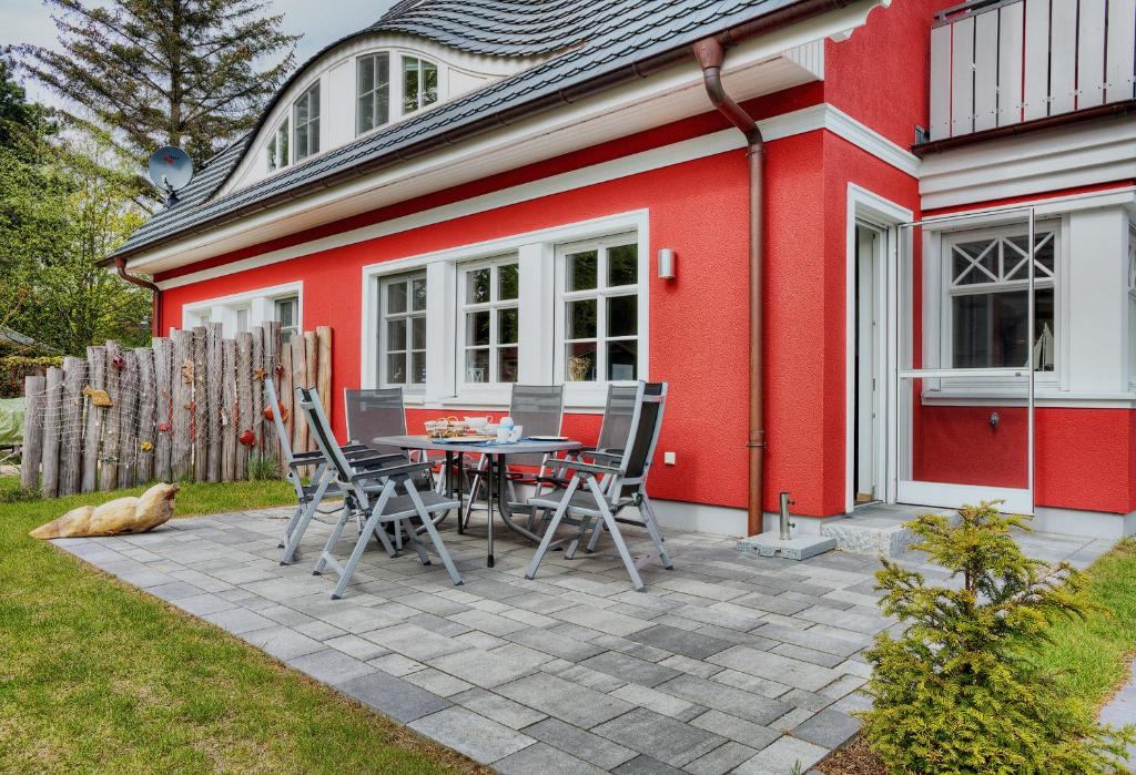 a patio with a table and chairs in front of a red house at Haus Strandmuschel in Zingst