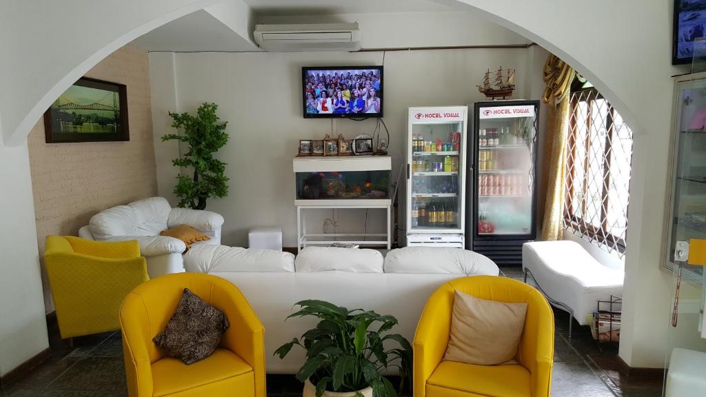 uma sala de estar com duas cadeiras amarelas e um sofá em HOTEL VISUAL em Balneário Camboriú