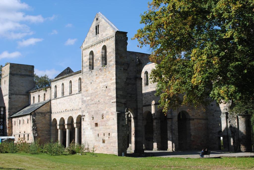 an old stone church with a tower and a tree at Fewo an der Klosterruine Paulinzella mit kostenfreien Parkplatz und WLAN in Königsee