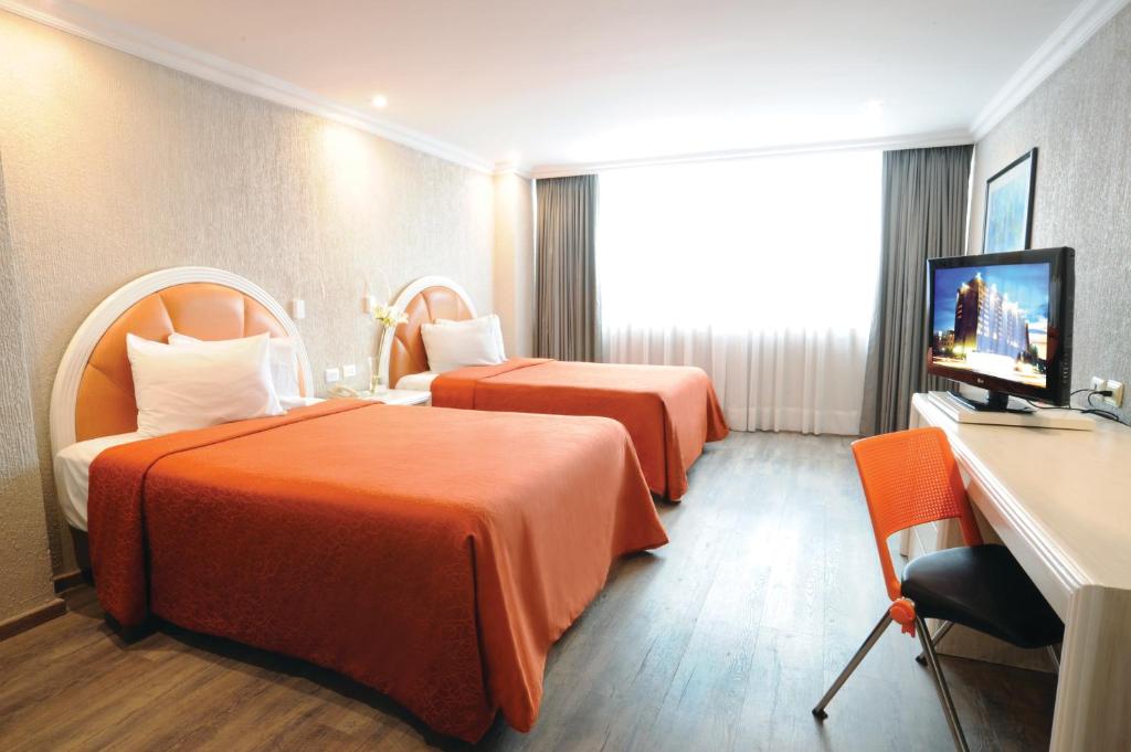 um quarto de hotel com duas camas e uma televisão de ecrã plano em Hotel Benidorm em Cidade do México
