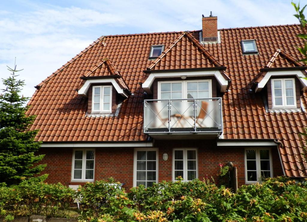 une maison avec un toit rouge et un balcon dans l'établissement Navigare, à Wyk auf Föhr
