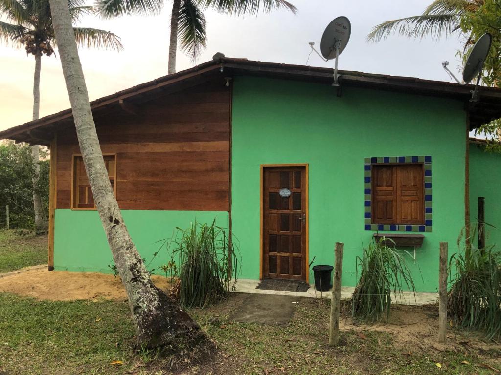 ein grünes Holzhaus mit einer Palme in der Unterkunft Chalezinho Super Equipado em Caravelas in Caravelas
