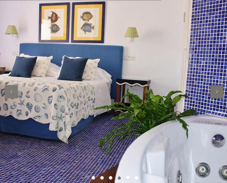 a bedroom with a blue bed and a bath tub at miKasa Agua Amarga & SPA in Agua Amarga