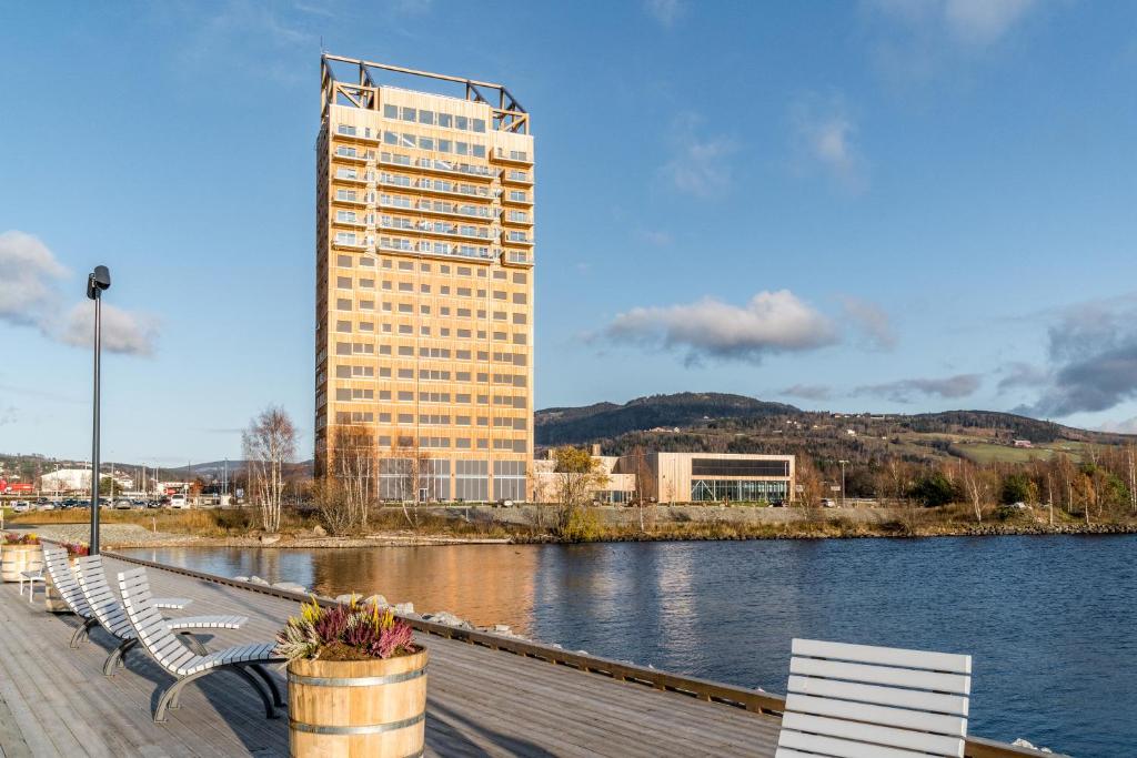 een rij banken op een steiger met een hoog gebouw bij MJOS TOWER Apartment - Lovely city view in Ringsaker