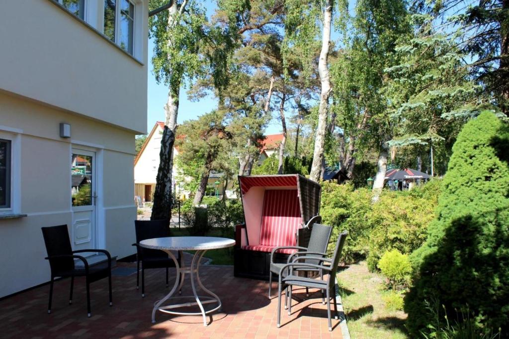 eine Terrasse mit einem Tisch, Stühlen und Bäumen in der Unterkunft Strandvilla Sophie App 1 in Dierhagen