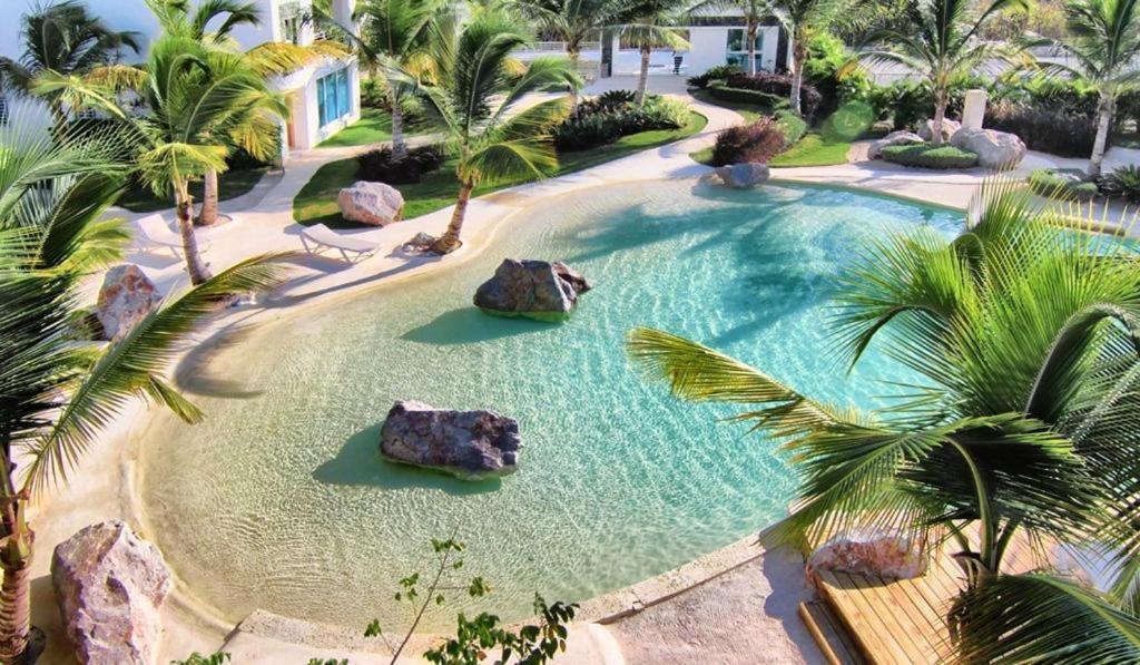 een groot zwembad met palmbomen en rotsen bij Casa en Paraiso RD in Bayahibe