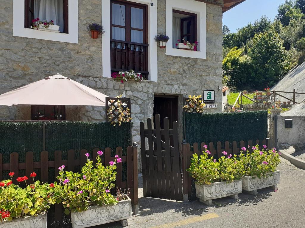 ein Haus mit Blumen vor einem Zaun in der Unterkunft Casa Rural La Peña en Unquera (Cantabria) in Unquera