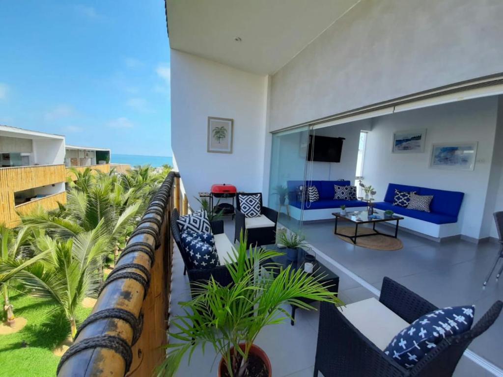uma varanda com mobiliário azul e branco e o oceano em Departamento Las Palmeras de Bocapan 308 em Tumbes
