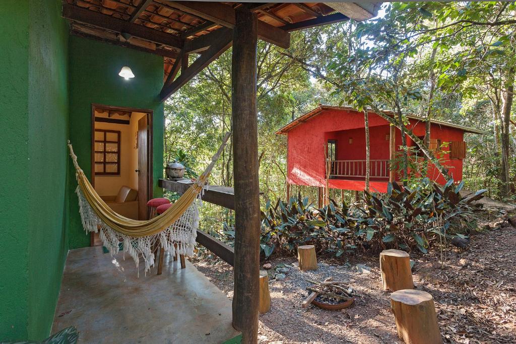 a hammock in front of a green and red house at Chalés do Beto em Macacos in Macacos