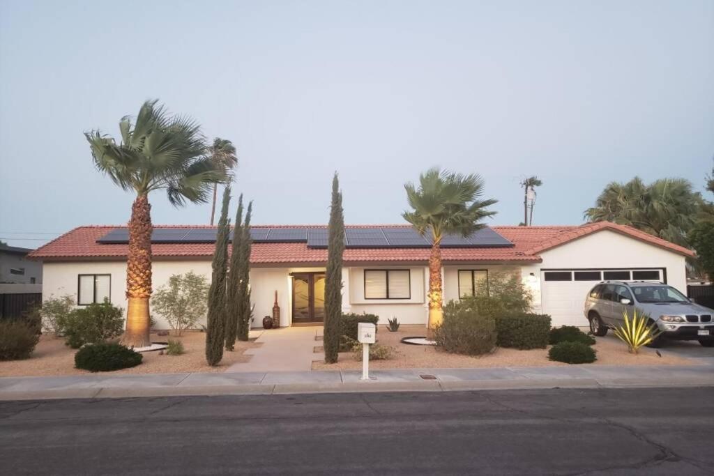 a house with palm trees and a car parked in front at Beautiful Palm Springs Home large private yard in Palm Springs