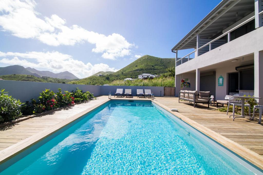 una piscina con terraza y una casa en Villa Jwi Lavi Boutique Hotel en Saint Martin