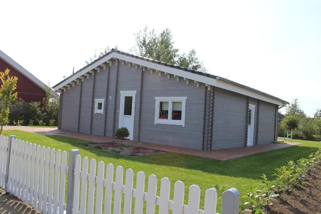 una pequeña casa gris con una valla blanca en Ferienhaus Harmonie en Twist